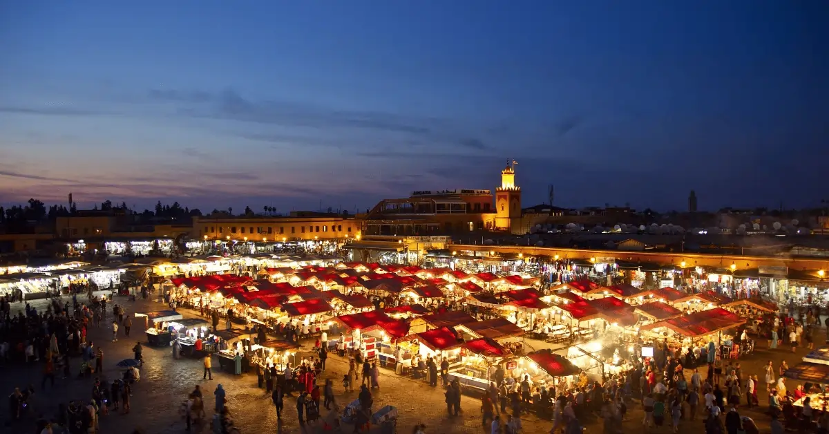 Tour Del Deserto da Fes a Marrakech in 4 Giorni 14 Jemaa el-Fnaa in Marrakesh at sunset with market stalls and crowds, featured as part of the 4 days tour from Marrakech to Merzouga.