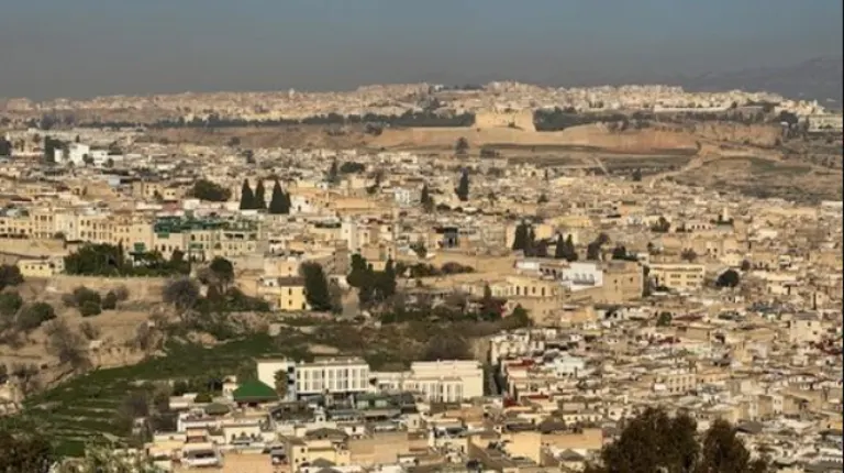8 Days Fes to Marrakech Desert Tour 2 Panoramic view of an ancient walled medina with dense historic buildings, narrow alleys, and traditional architecture by Morocco Fun Tours.