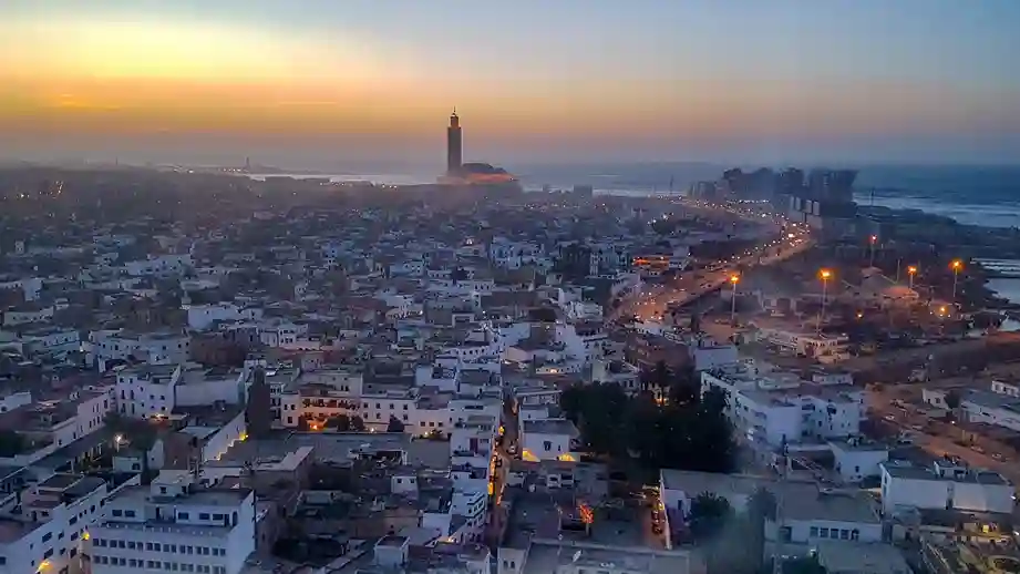A imagem mostra a cidade de Casablanca, Marrocos, com uma mesquita imponente em primeiro plano ao pôr do sol.