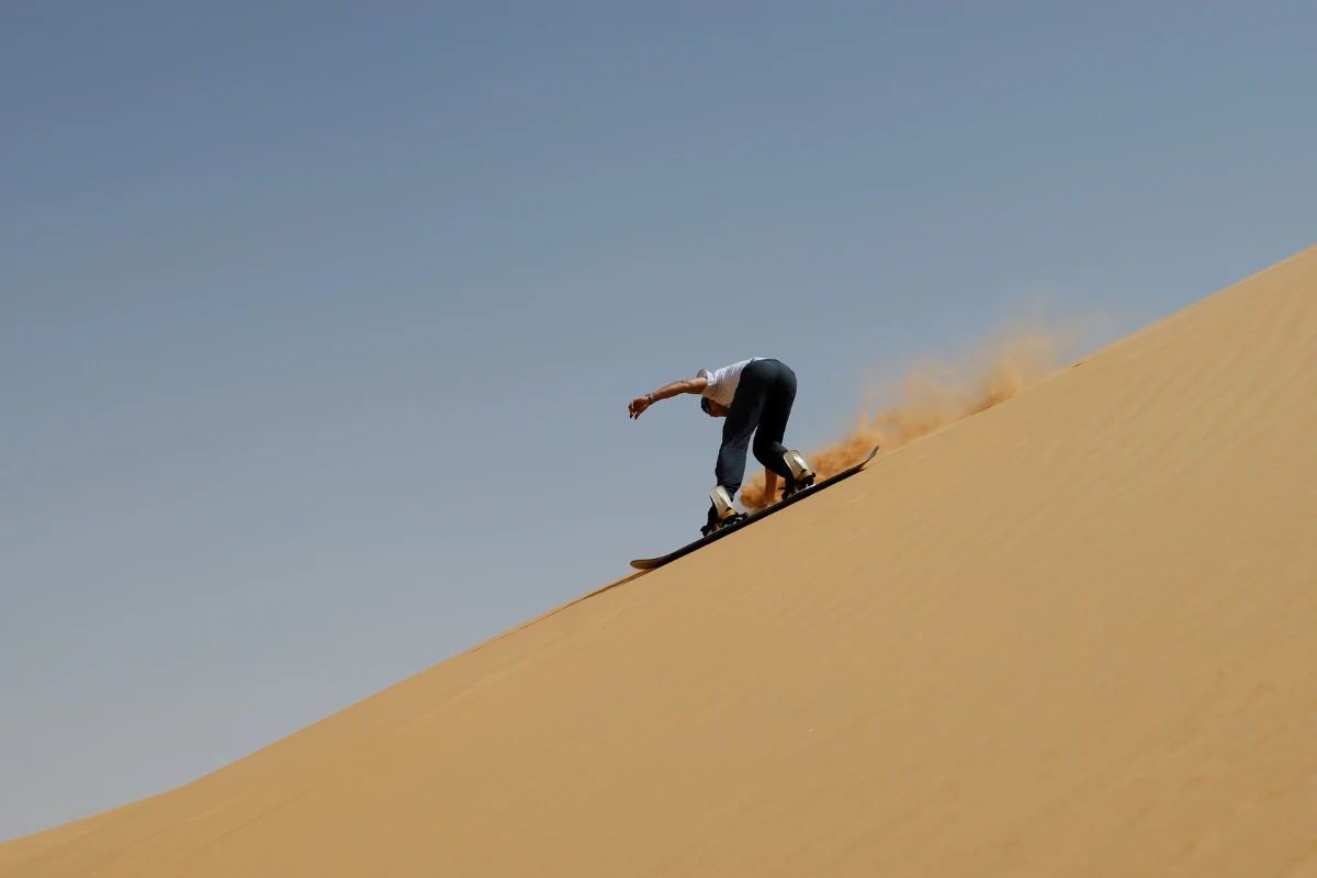 a person Sandboarding Marrakech on golden dunes near Agadir.
