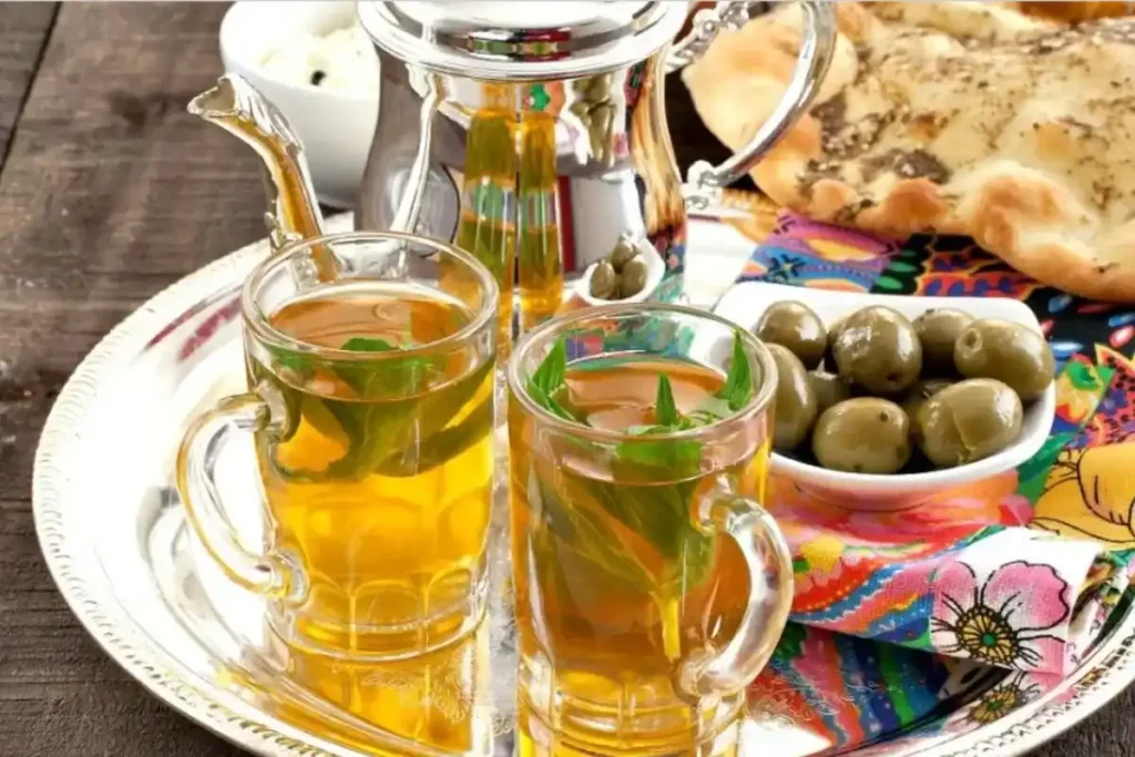 Traditional Moroccan mint tea in ornate glasses with fresh mint leaves - Morocco Weird Facts about hospitality culture and ceremonial preparation.