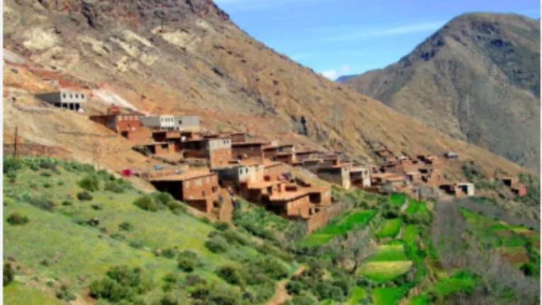 4 Days Tour from Marrakech 2 Traditional Berber village in Atlas foothills with terraced fields, river valley surroundings, and earthy houses blending into mountain landscape