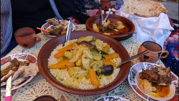 Traditional couscous meal with vegetables and meat served in clay dish during Atlas Marrocos trekking experience in mountain setting