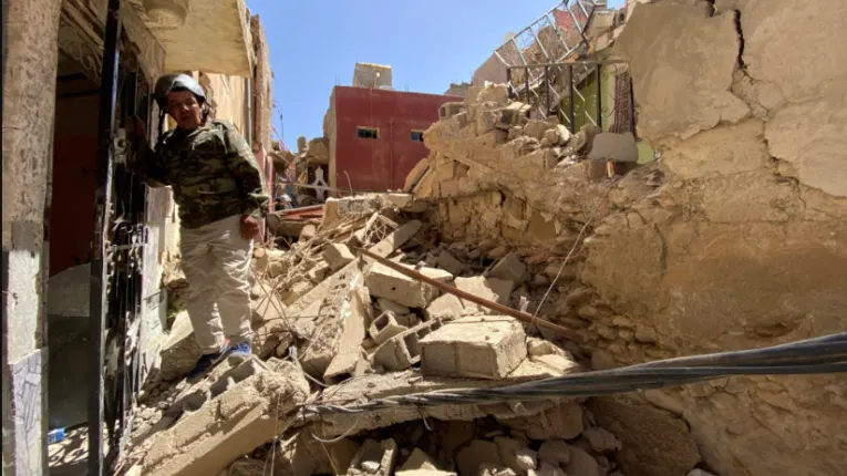 Collapsed homes and heavy rubble in Marrakesh Safi region after powerful earthquake, with damaged streets and residents navigating debris