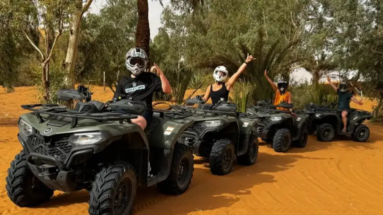 Tourists riding quad bikes across desert dunes with guided adventure experience organized by Morocco Fun Tours in Merzouga region