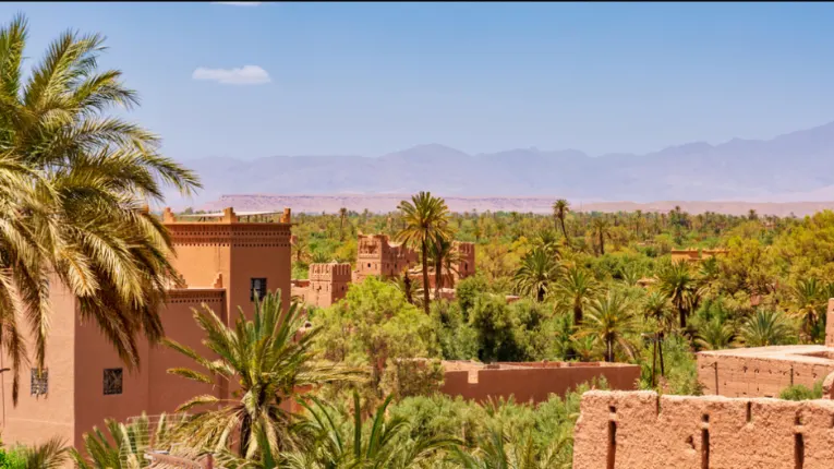 Kasbah Amridil in Skoura Oasis with mud brick towers, palm groves, and Atlas Mountains surrounding the historic fortress