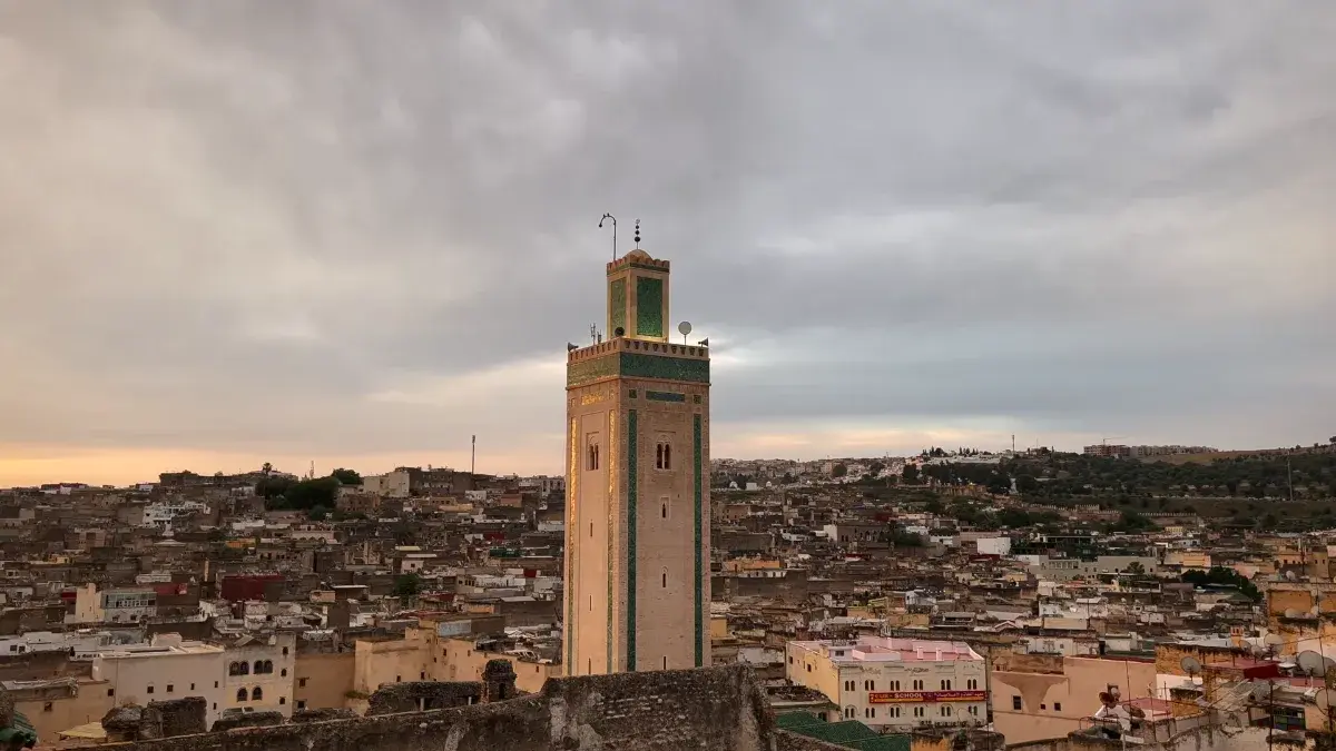 Panoramic view of the historic Fes Medina with a traditional minaret at sunset